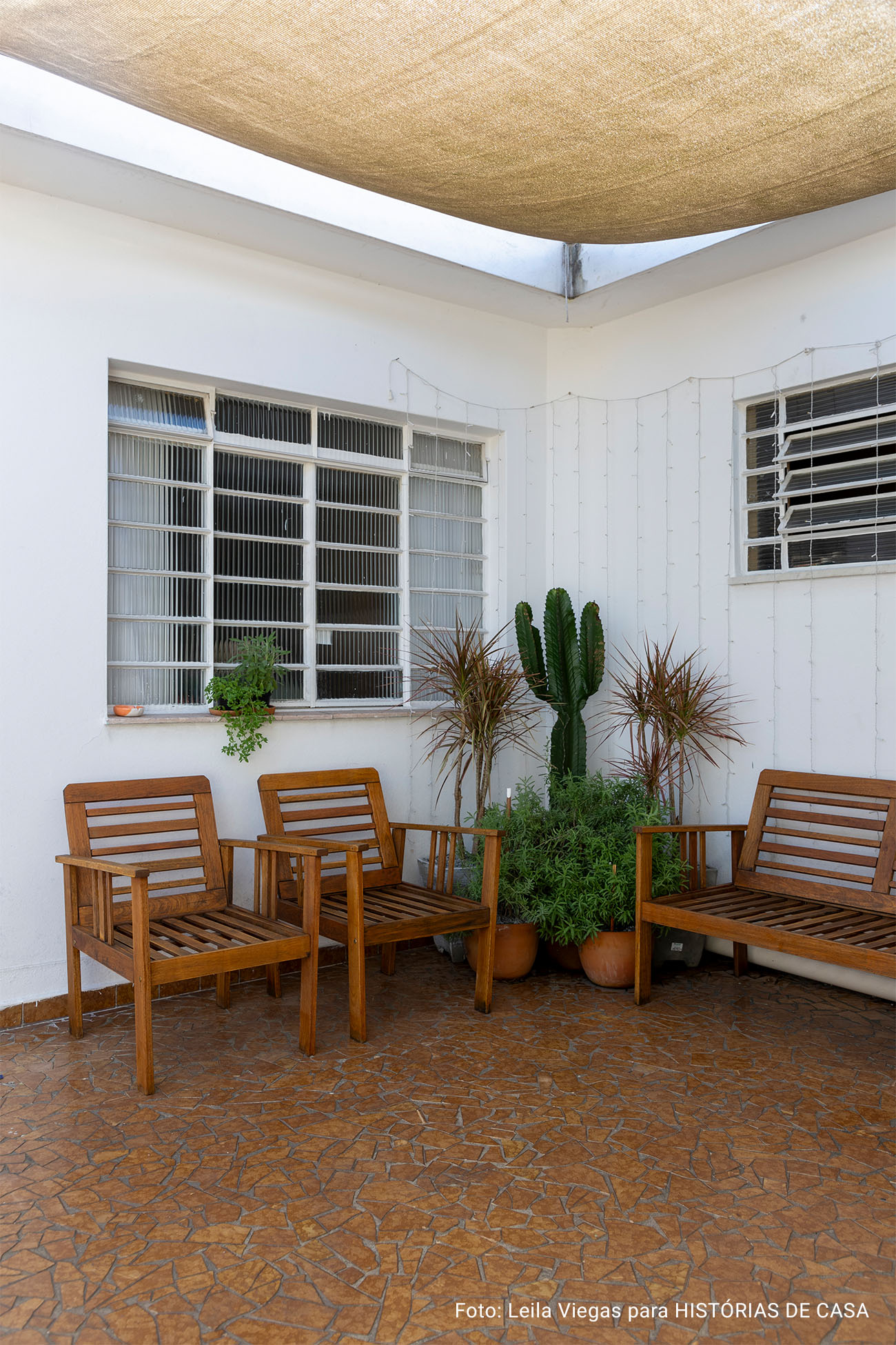 Casa de vó com decoração acolhedora e quintal com rede e plantas e piso de caquinho.