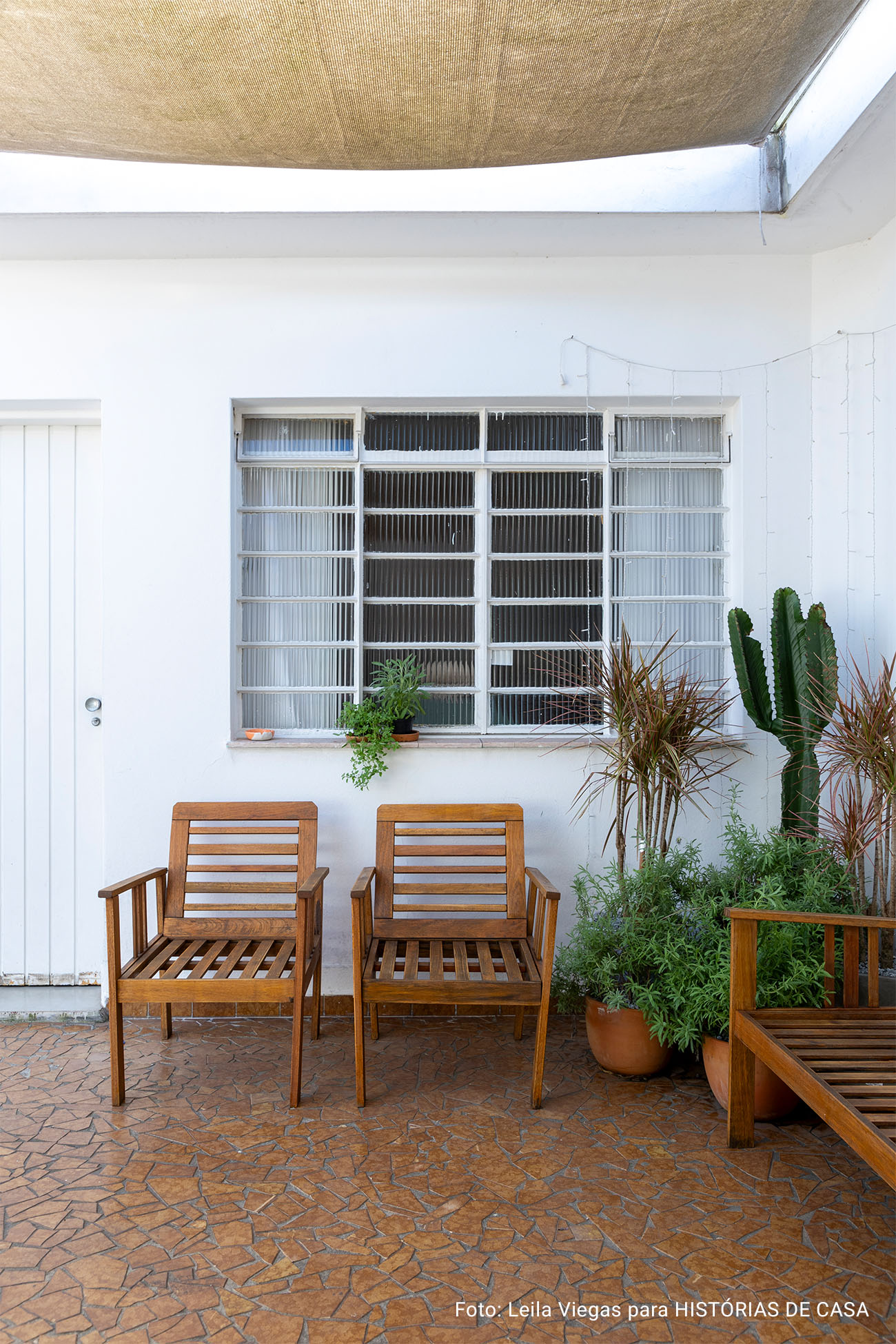 Casa de vó com decoração acolhedora e quintal com rede e plantas e piso de caquinho.