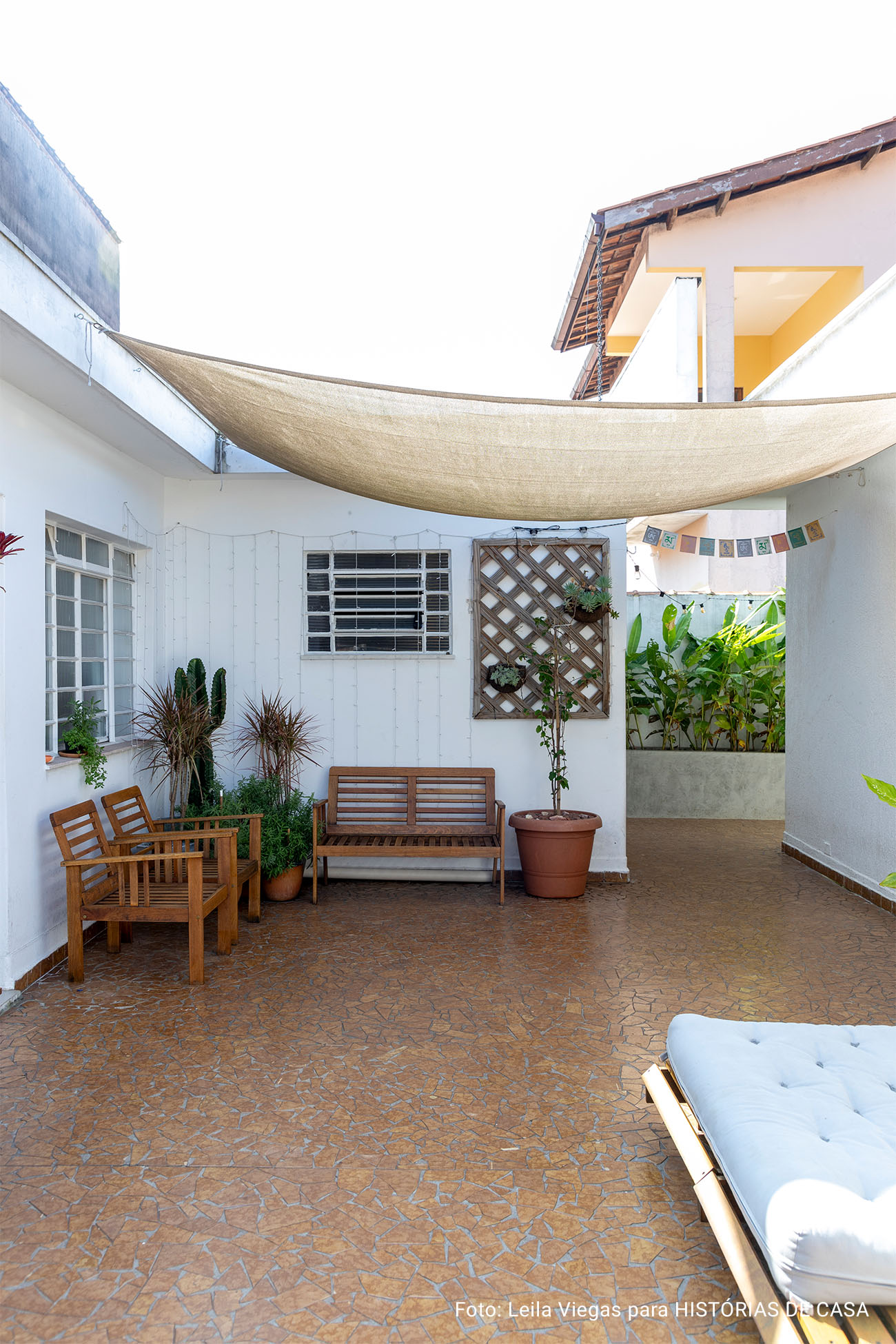 Casa de vó com decoração acolhedora e quintal com rede e plantas e piso de caquinho.