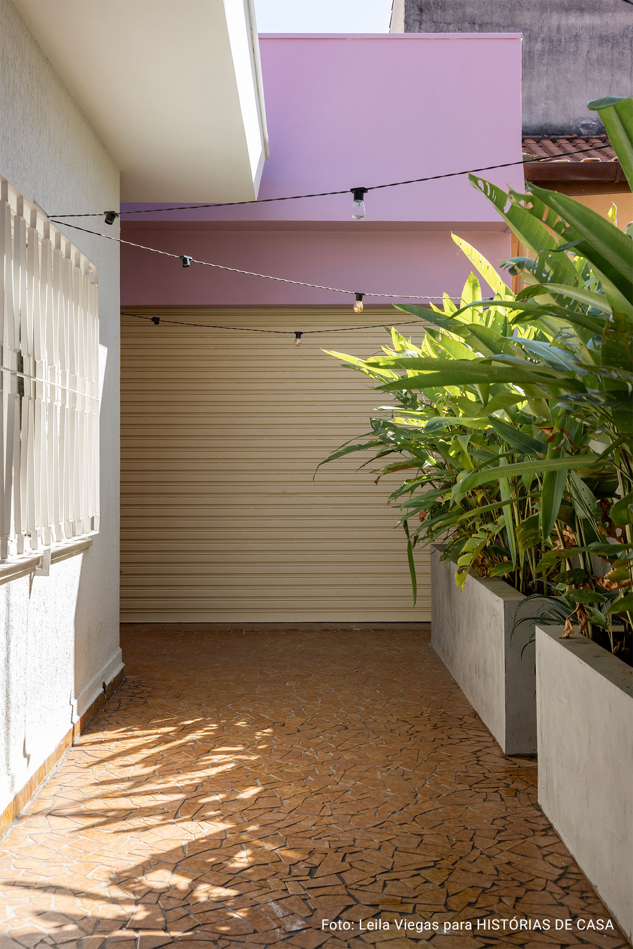 Casa de vó com decoração acolhedora e quintal com rede e plantas e piso de caquinho.