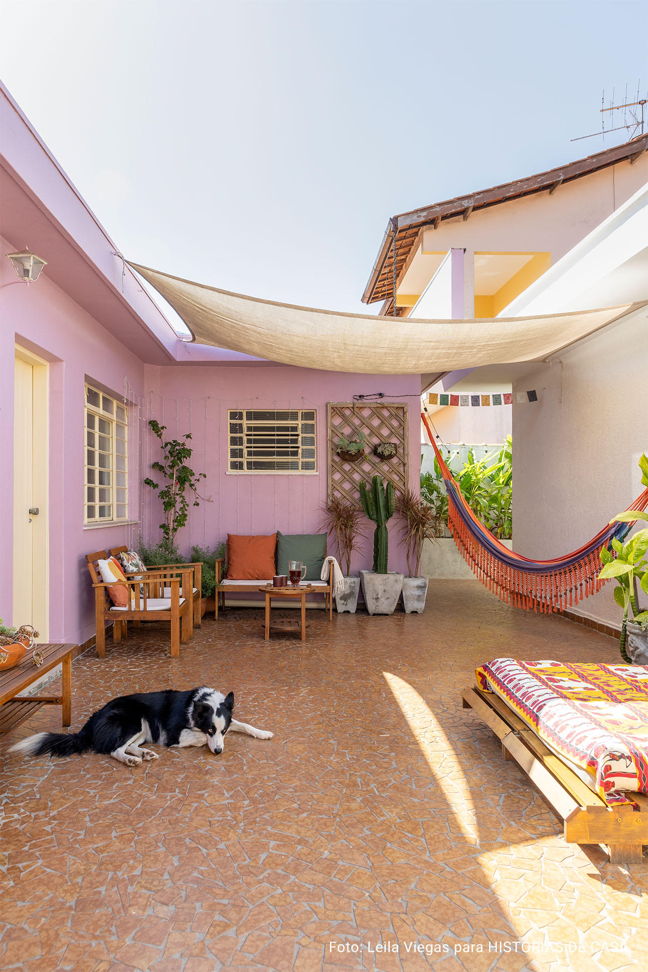 Casa de vó com decoração acolhedora e quintal com rede e plantas e piso de caquinho.