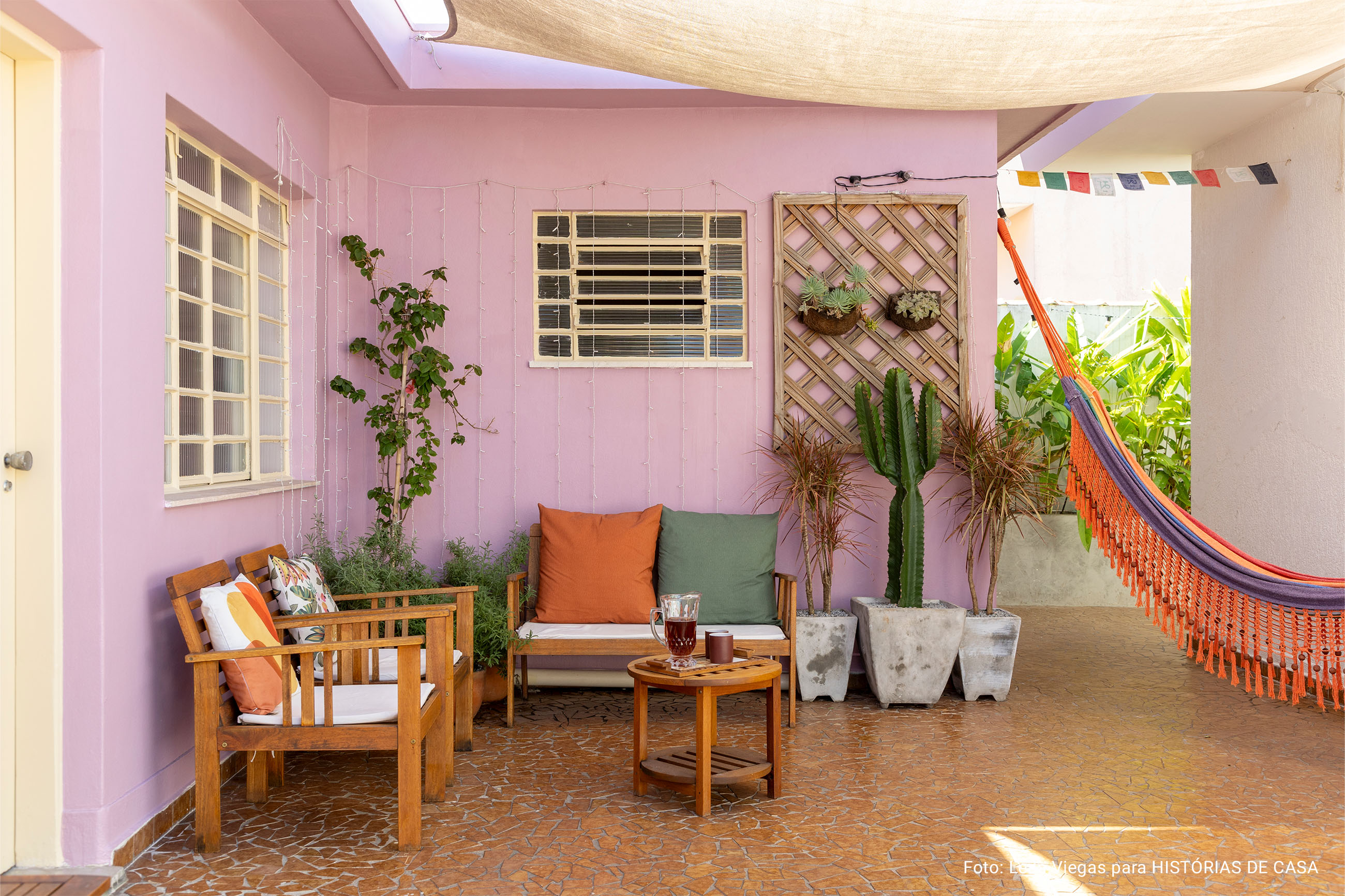 Casa de vó com decoração acolhedora e quintal com rede e plantas e piso de caquinho.