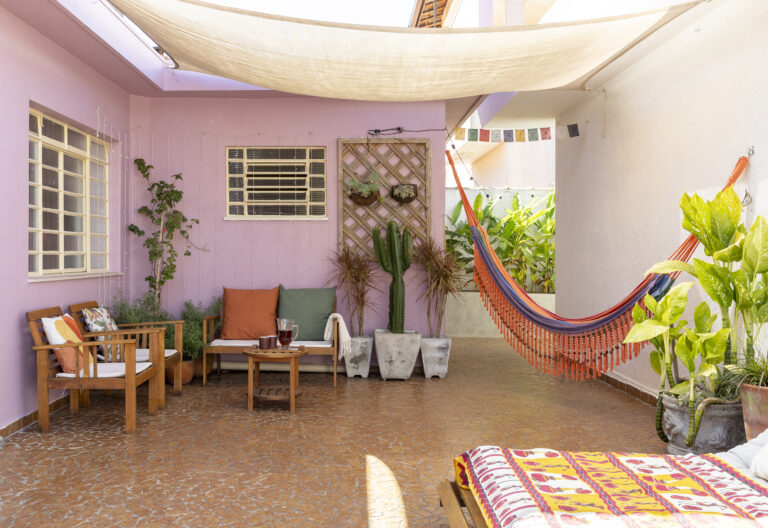 Casa de vó com decoração acolhedora e quintal com rede e plantas e piso de caquinho.