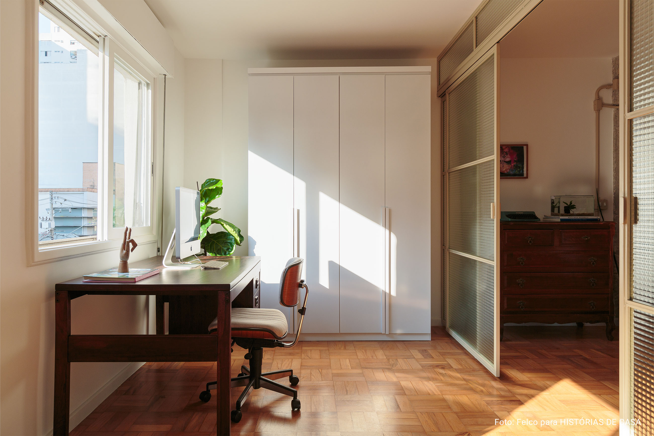 Apartamento minimalista com cozinha integrada, piso de caquinhos e porta de serralheria