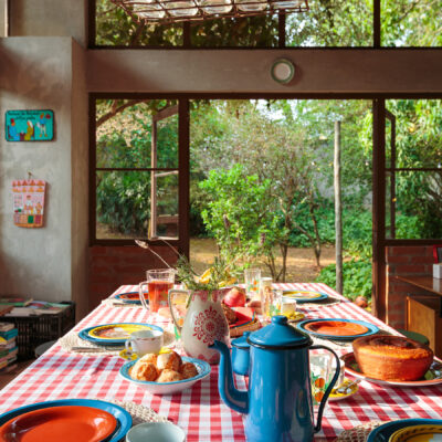 Casa de campo com cozinha aberta para a natureza e mesa posta com louças da Tok&Stok